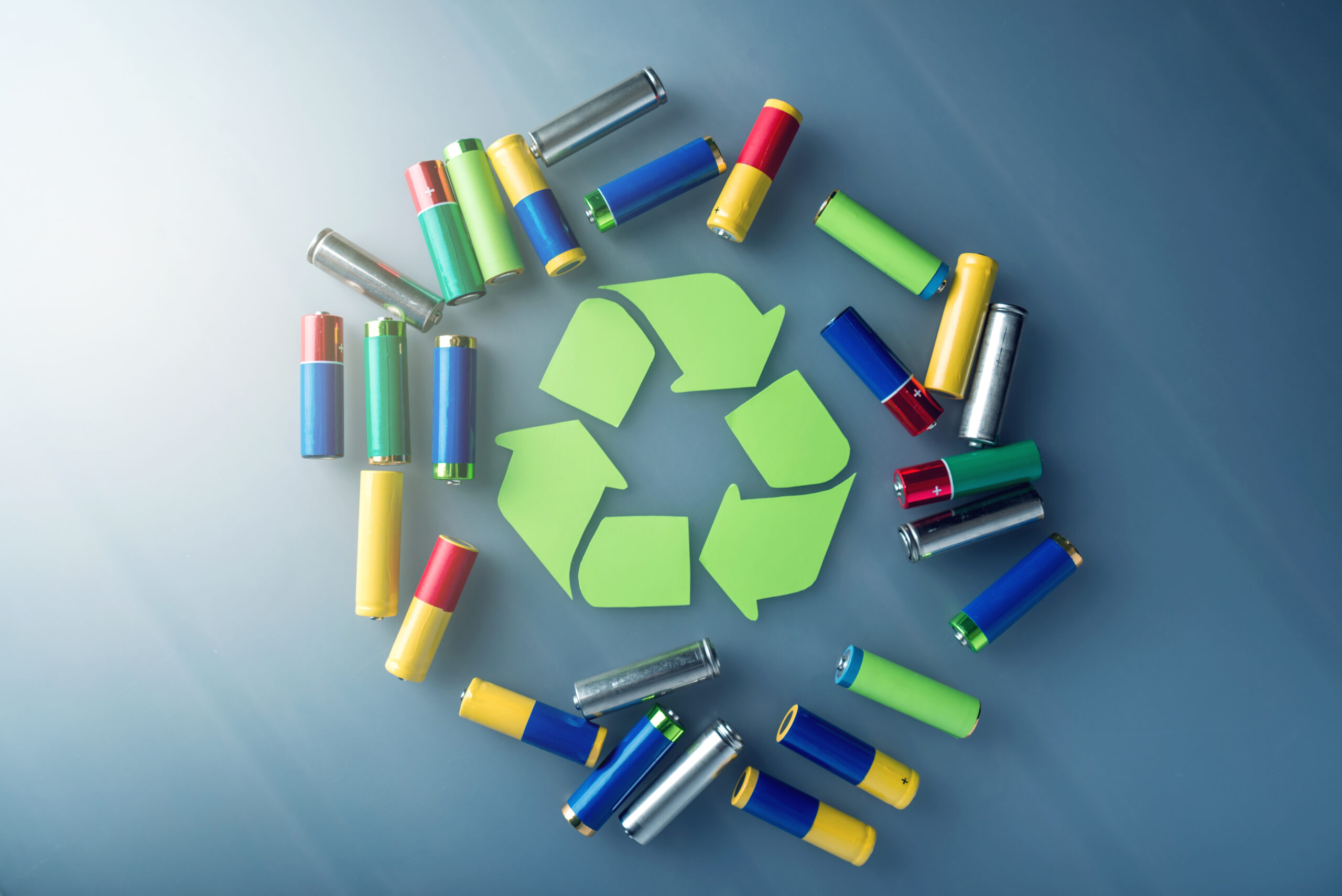 Used AA and proper disposal of toxic to the environment and soil batteries on a blue background. The concept of technologies of processing of harmful and recycling substances for ecological