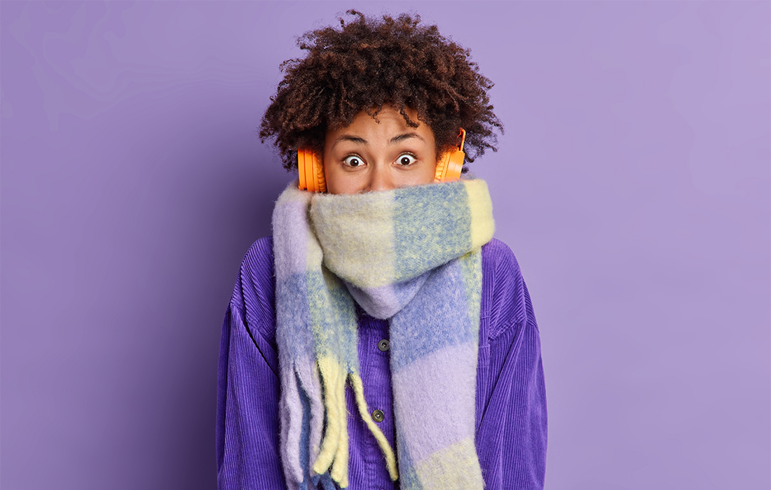 woman in cosy scarf, hiding face, purple background