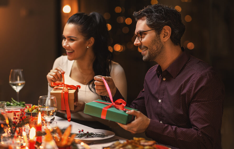 Couple opening gifts at Christmas table Pic: Shutterstock