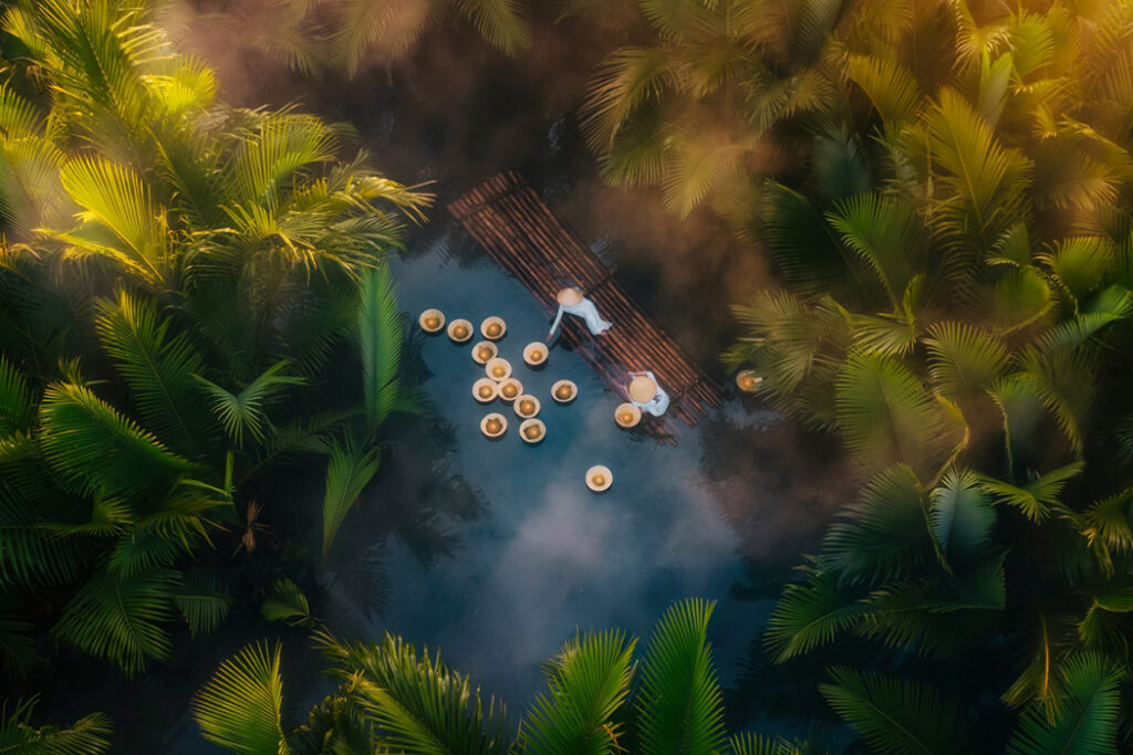 Two people release flowers on the river in Quang Ngai, Vietnam as a symbolic gesture. Photographed by Sinh Nguyen Duy.