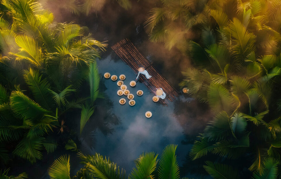 Two people release flowers on the river in Quang Ngai, Vietnam as a symbolic gesture. Photographed by Sinh Nguyen Duy.