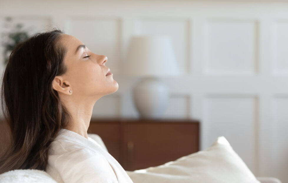 Close up profile view of tired young caucasian woman rest on couch at home with eyes closed dreaming or sleeping, female relax on sofa breathe fresh air, relieve negative emotion, stress free concept