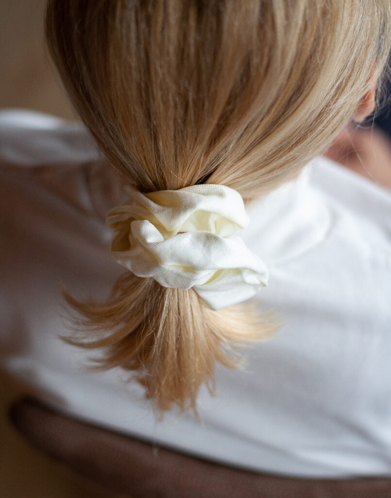 Blonde woman with hair tied back with a cream silk scrunchie