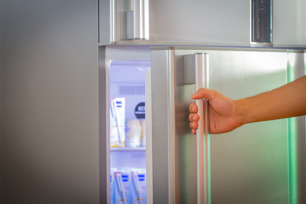 Woman's hand opens stainless steel fridge