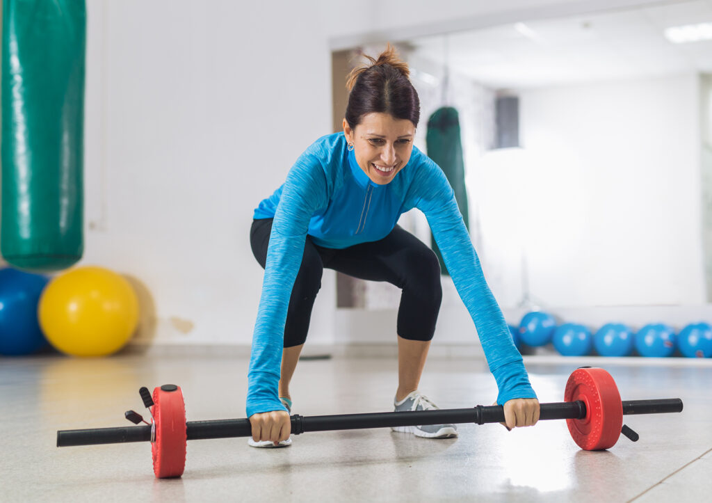 Woman at gym lifting bar weight