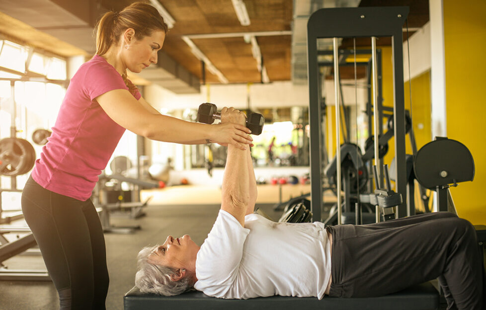 personal trainer working exercise with senior woman in the gym.