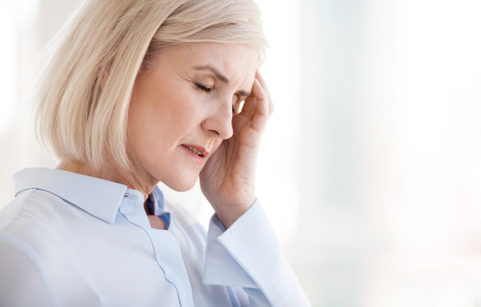 Tired upset mature old businesswoman suffering from strong chronic headache migraine or memory loss at work, stressed dizzy fatigued middle aged senior woman office worker feels pain in aching head;