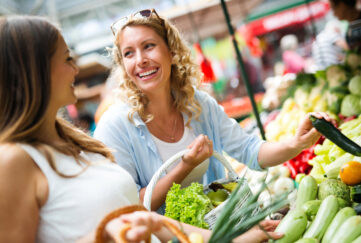 Young happy women shopping vegetables and fruits on the market;