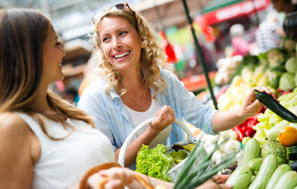 Young happy women shopping vegetables and fruits on the market;