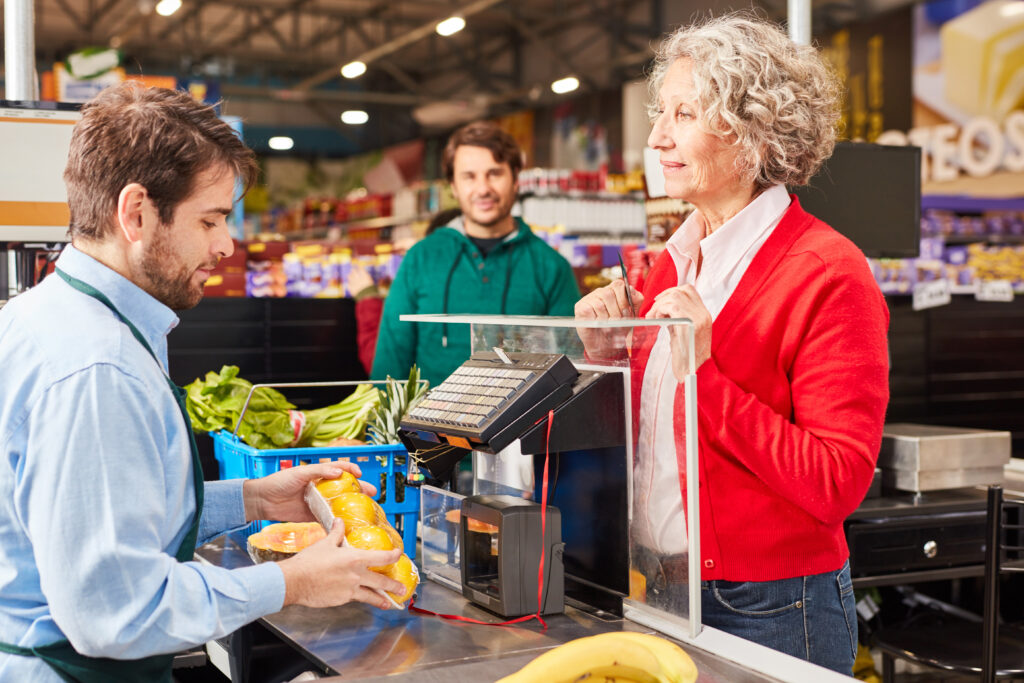 Older women shopping in supermarket at till