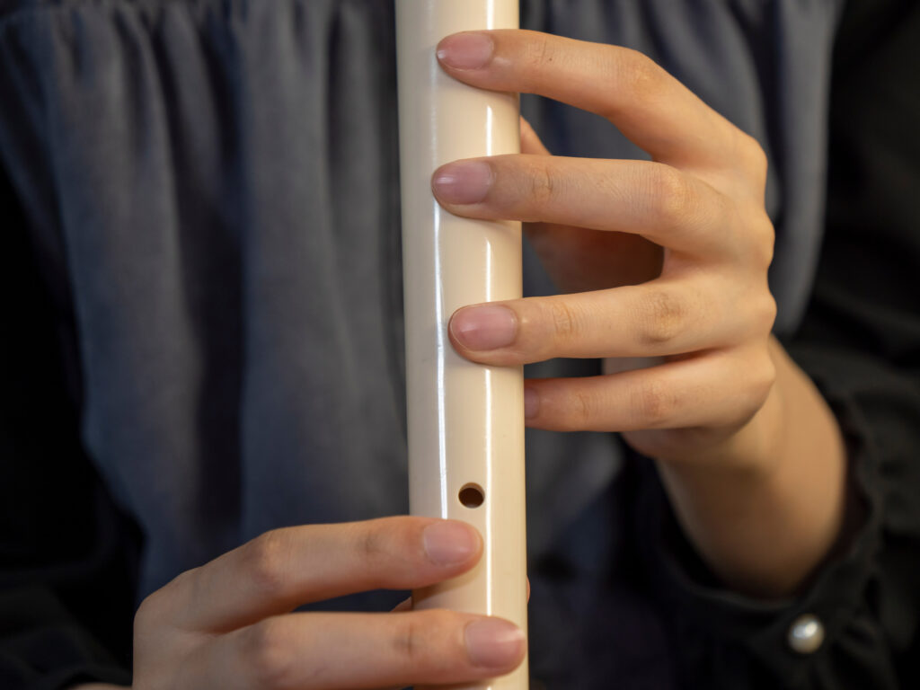 Closeup of woman hand while playing alto recorder; 