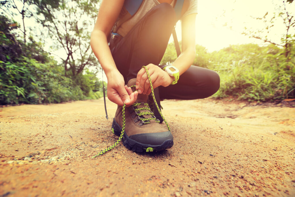 woman hiking tying shoelace on forest trail; 