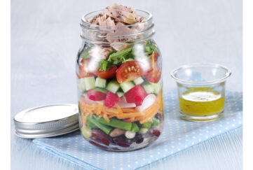 Jar of layered salad with small jar of dressing