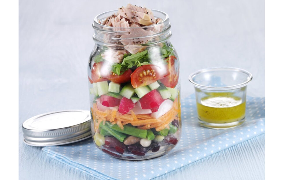 Jar of layered salad with small jar of dressing