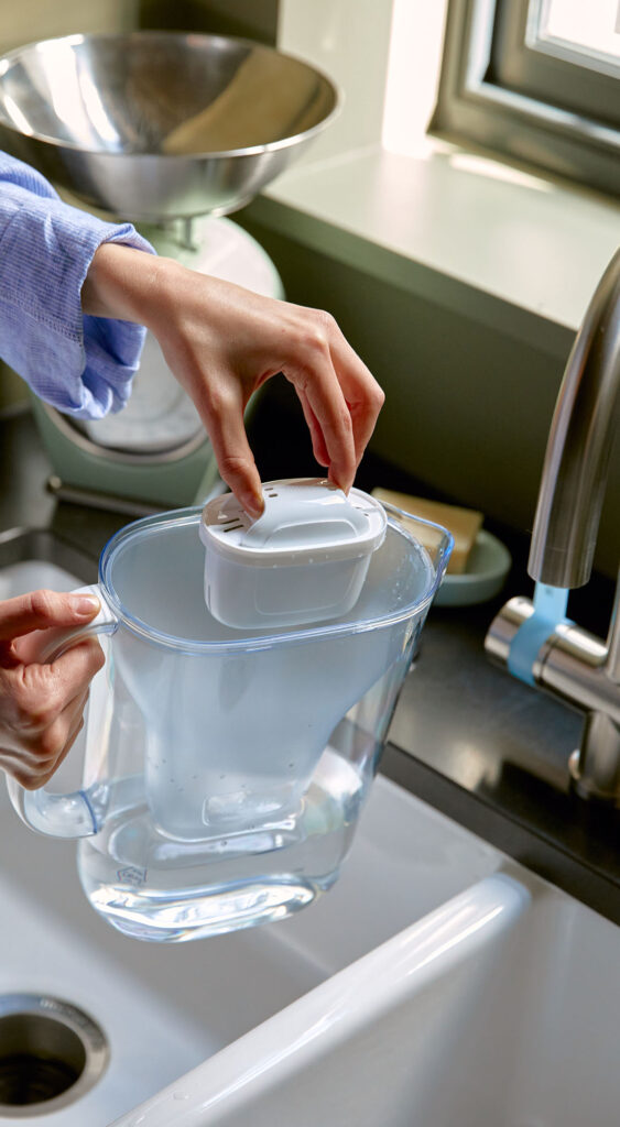 Woman filling BRITA jug at the kitchen sink