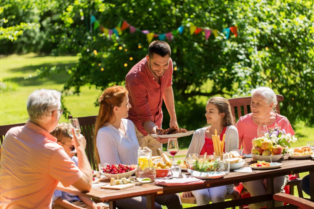 leisure, holidays and people concept - happy family having festive dinner or summer garden party; 