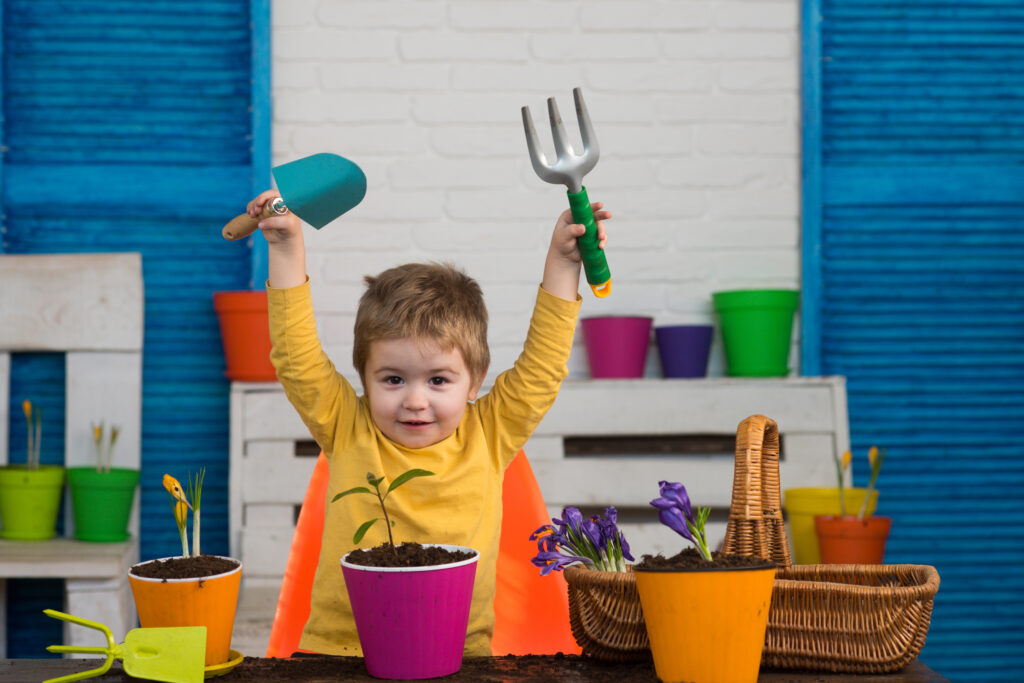 Tools for gardening. Garden equipment. Little gardener. Spade to plant flowers in pots. Happy child.;