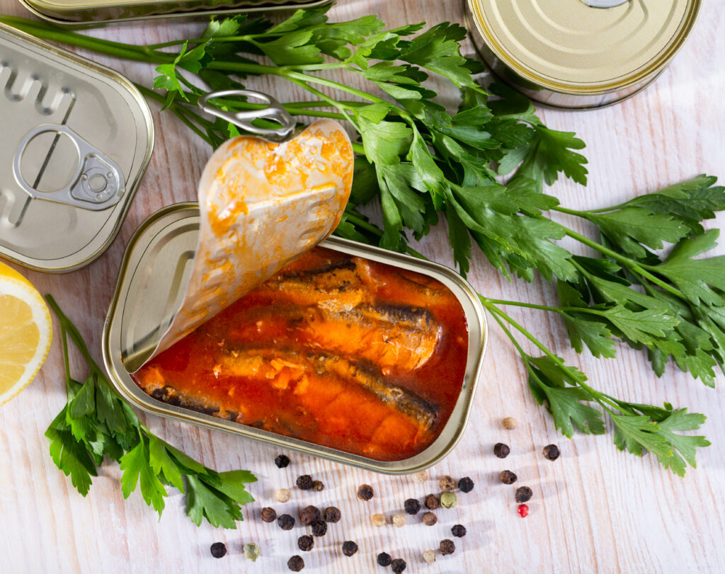 Image of pickled sardines in tomato sauce in open tin can, 