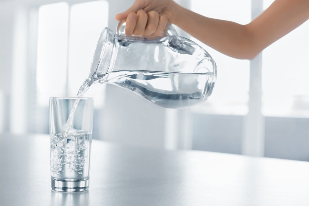 Drink Water. Woman's Hand Pouring Fresh Pure Water From Pitcher Into A Glass. Health And Diet Concept. Healthy Lifestyle. Healthcare And Beauty. Hydratation.; 