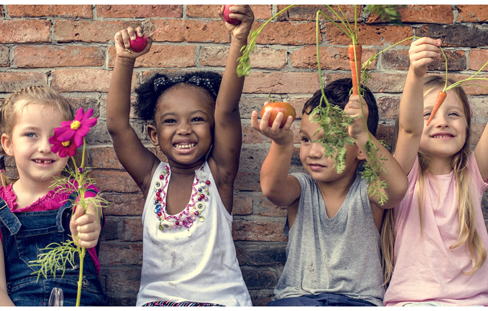 Group of kindergarten kids learning gardening outdoors;