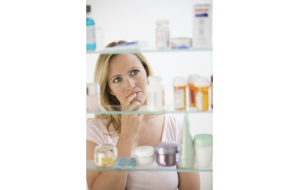 Woman looking in bathroom medicine cabinet