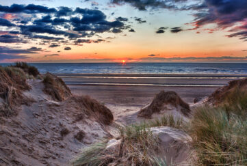 Sun setting over the beach at Formby in England through sand dunes