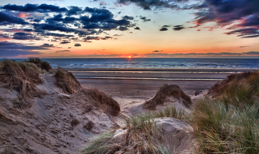 Sun setting over the beach at Formby in England through sand dunes