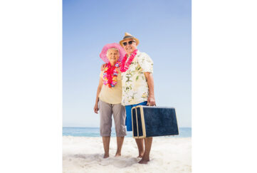 Senior couple holding suitcase on the beach