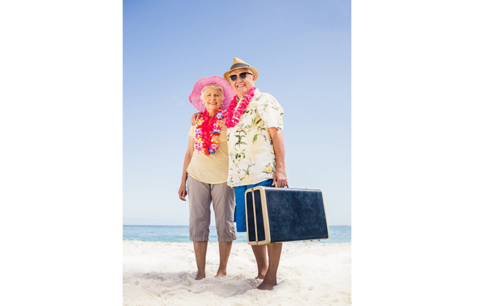 Senior couple holding suitcase on the beach