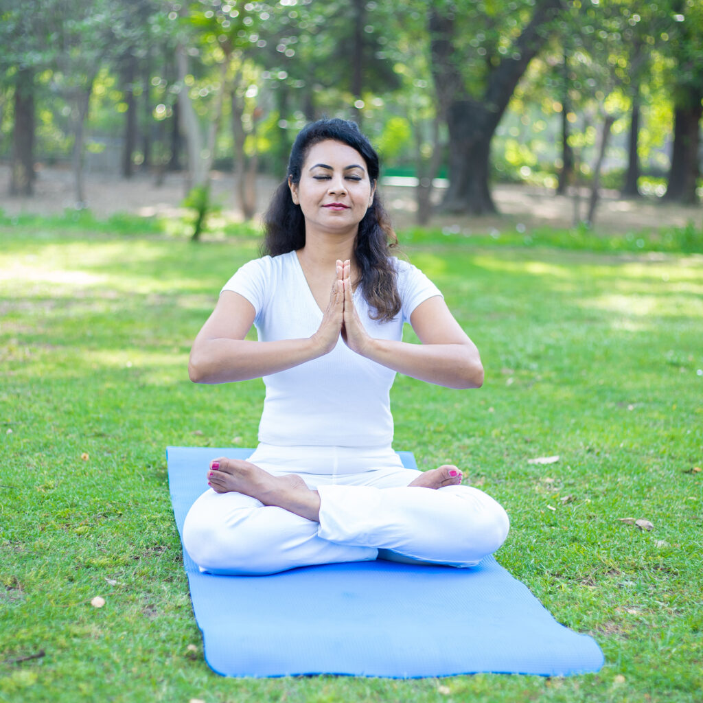 Beautiful indian woman doing breathing yoga exercise in the park