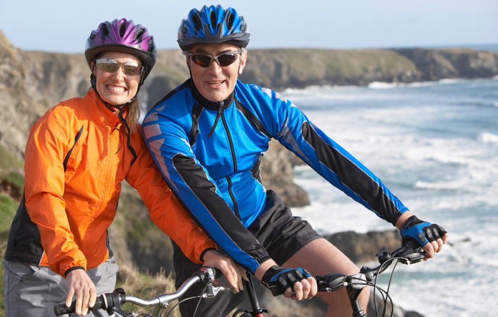 A mature couple cycling by the coast