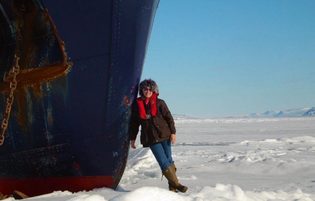 Amelia standing on snow beside a very large boat
