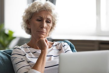 Lady looking pensive at her laptop wondering if she is being scammed Pic: Shutterstock