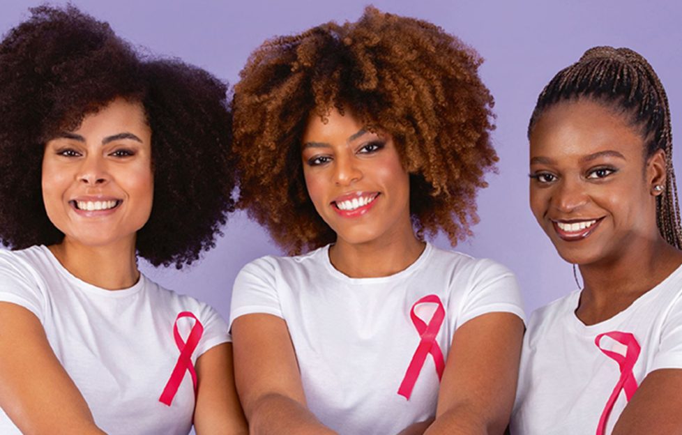 Three women wearing white t-shirts with pink ribbon for breast cancer charity