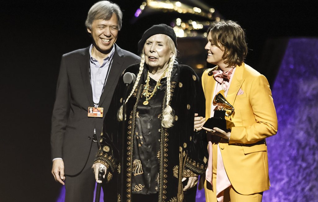 Singer-songwriter Joni Mitchell (C) accepts the Best Folk Album Grammy Award for "Joni Mitchell At Newport [Live]" with US singer-songwriter Brandi Carlile (R) during the Premiere Ceremony at the 66th annual Grammy Awards 2024