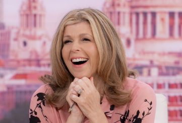 This is Your Life Kate Garraway possible new host of iconic reboot. Image features Kate on Good Morning Britain. She's smiling wide and resting her chin on her hand. She's wearing a pale pink blouse with black floral decoration.