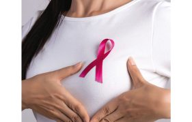 A woman proudly wearing her pink ribbon for Breast Cancer Now