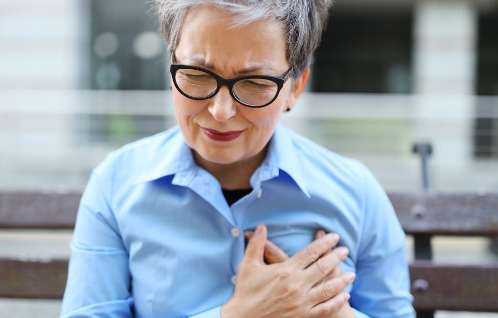 Older woman clutching chest.