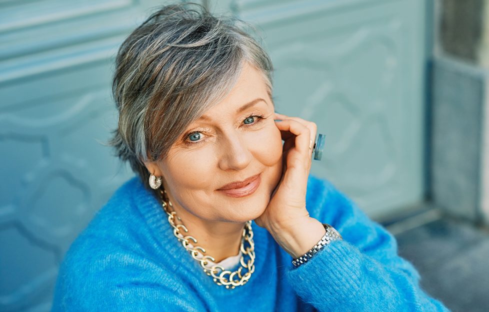 Outdoor portrait of beautiful 55 - 60 year old woman, wearing blue pullover