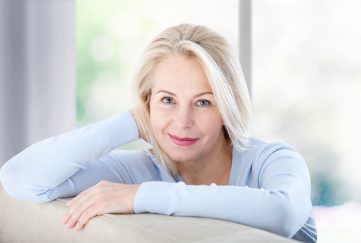 Middle-aged lady at home leaning on the back of her sofa