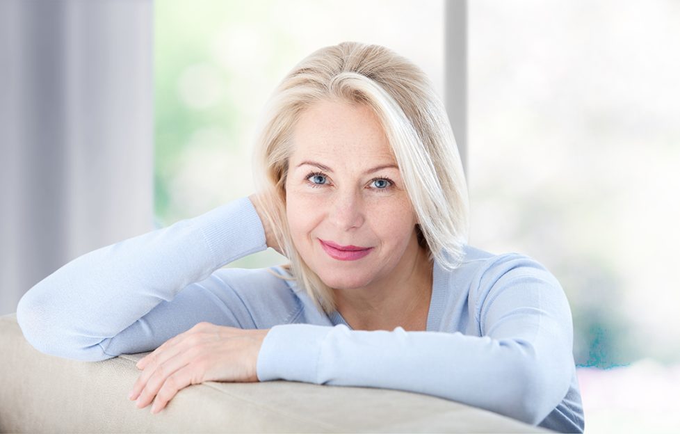 Middle-aged lady at home leaning on the back of her sofa