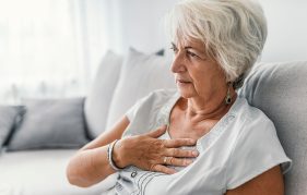 An older lady who is out of breath, sitting on sofa at home