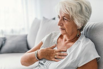 An older lady who is out of breath, sitting on sofa at home