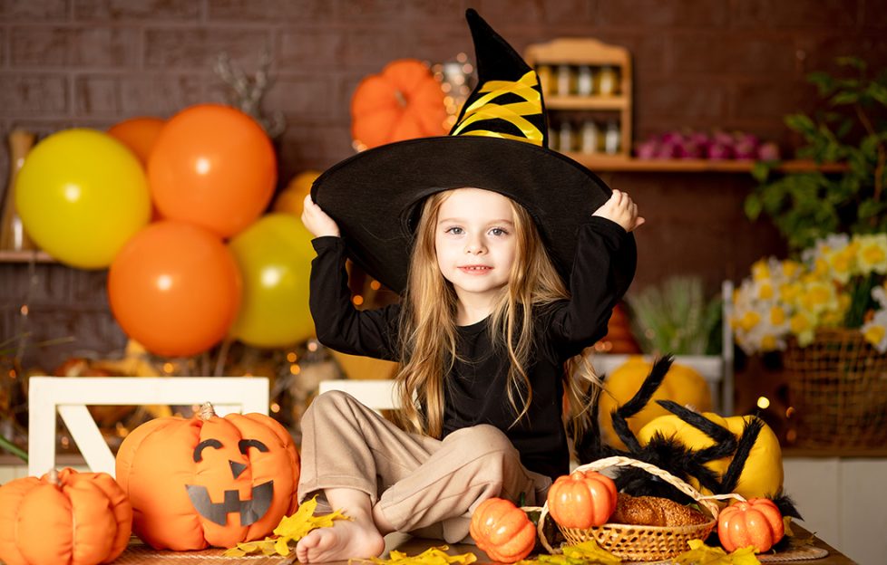 A little girl dressed as a witch with Halloween decorations