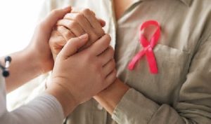 A relative holding hands with a patient as she tells her breast cancer story