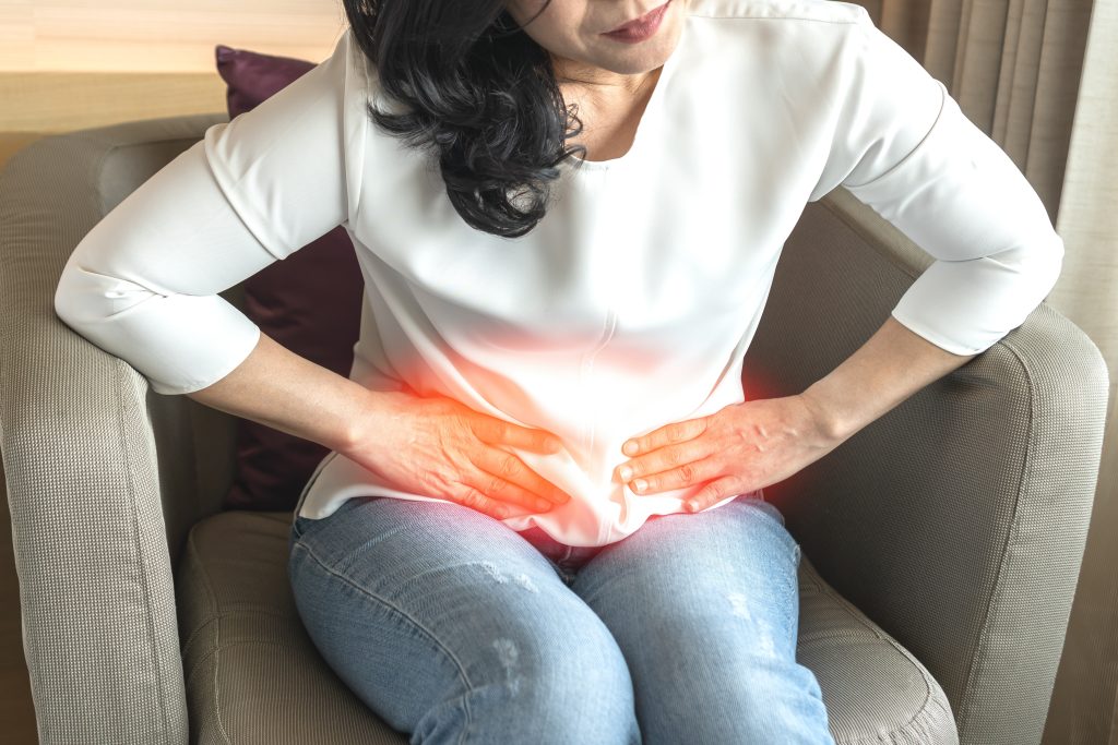 sitting woman leans over due to stomachache