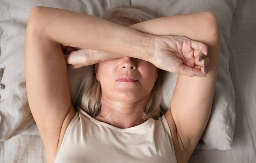 Woman covering eyes with her arms, she has a migraine