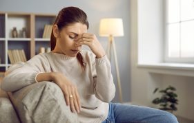 Woman with migraine at home on sofa