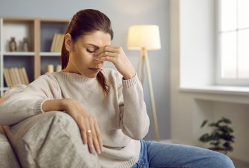 Woman with migraine at home on sofa