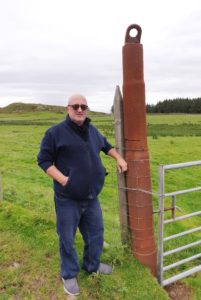 Michael Martin with one of the Aska's gantry crane strain arms which was salvaged and is now used as a gate post on Gigha.